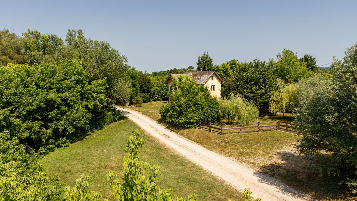 House set well back on a large rural lot with a gravel track and open field