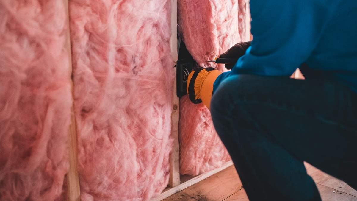 Insulation and moisture control being installed between floor framing