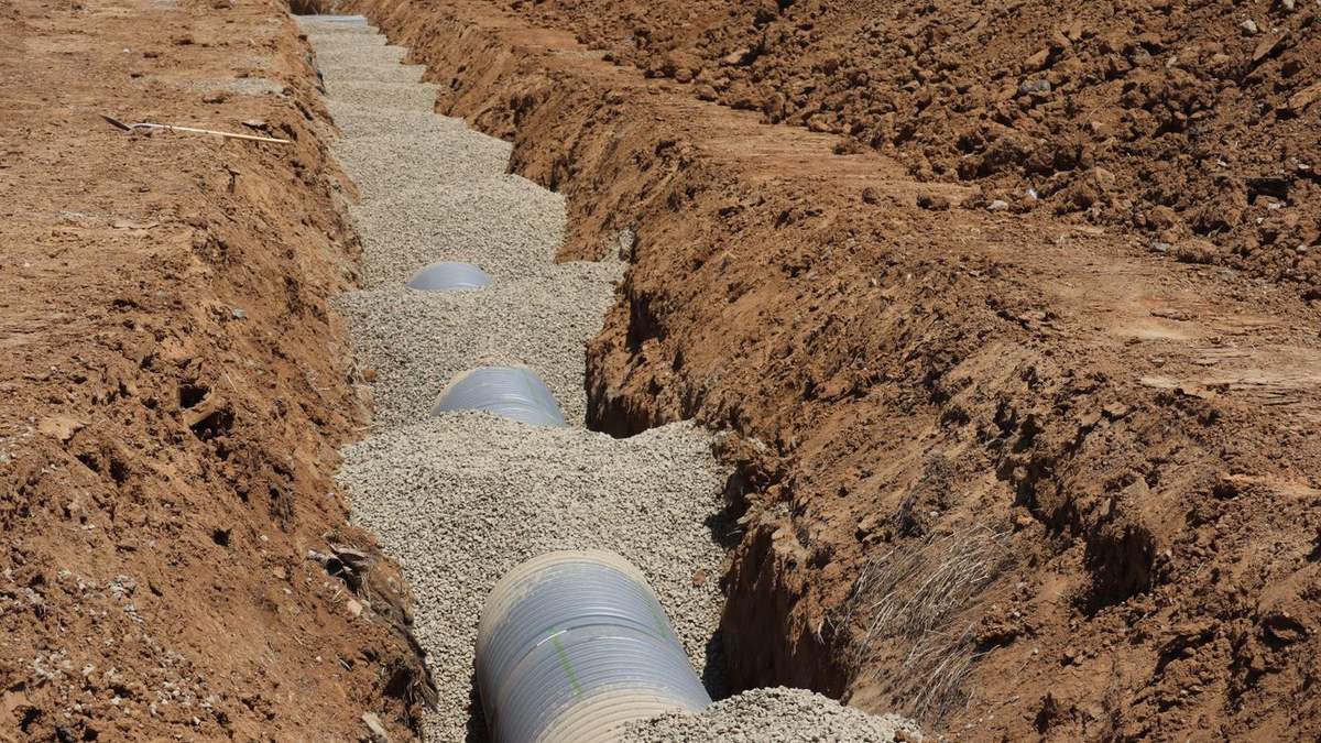 Perforated drainage pipe bedded in gravel in an open trench