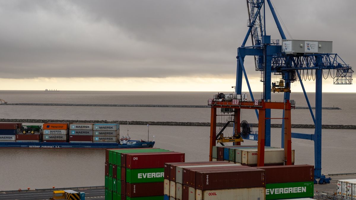 Stacked shipping containers and a gantry crane at a river container terminal