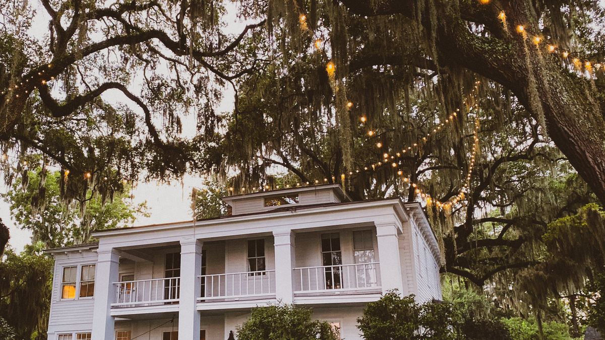 Raised Southern house with double porches under live oaks draped in Spanish moss