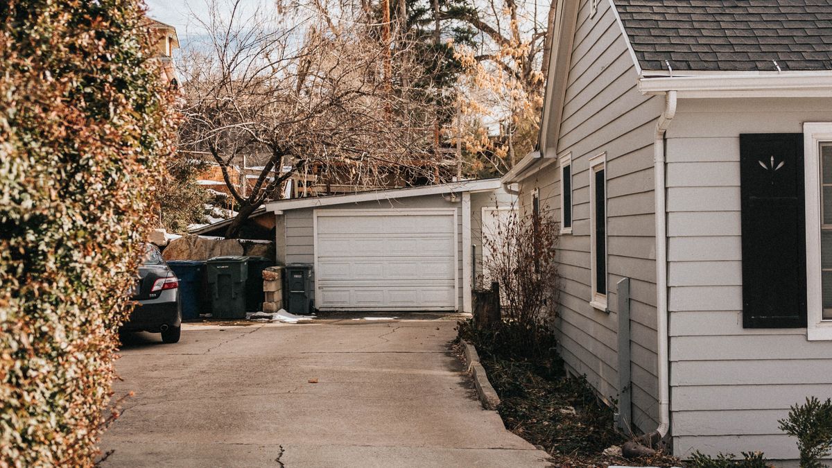Cracked concrete driveway running alongside a suburban house and garage